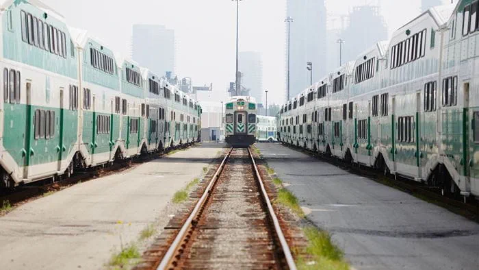 GO Transit train yard with train coming towards camera from afar, trains flanking on adjacent tracks