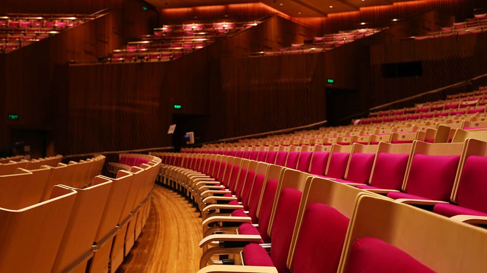 Rows of seats with red velvet cushions inside the Concert Hall at the Sydney Opera House