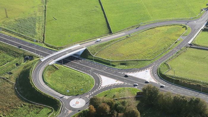 Aerial shot of M17/M18, showing a flyover and roundabout, with fields alongside the road.