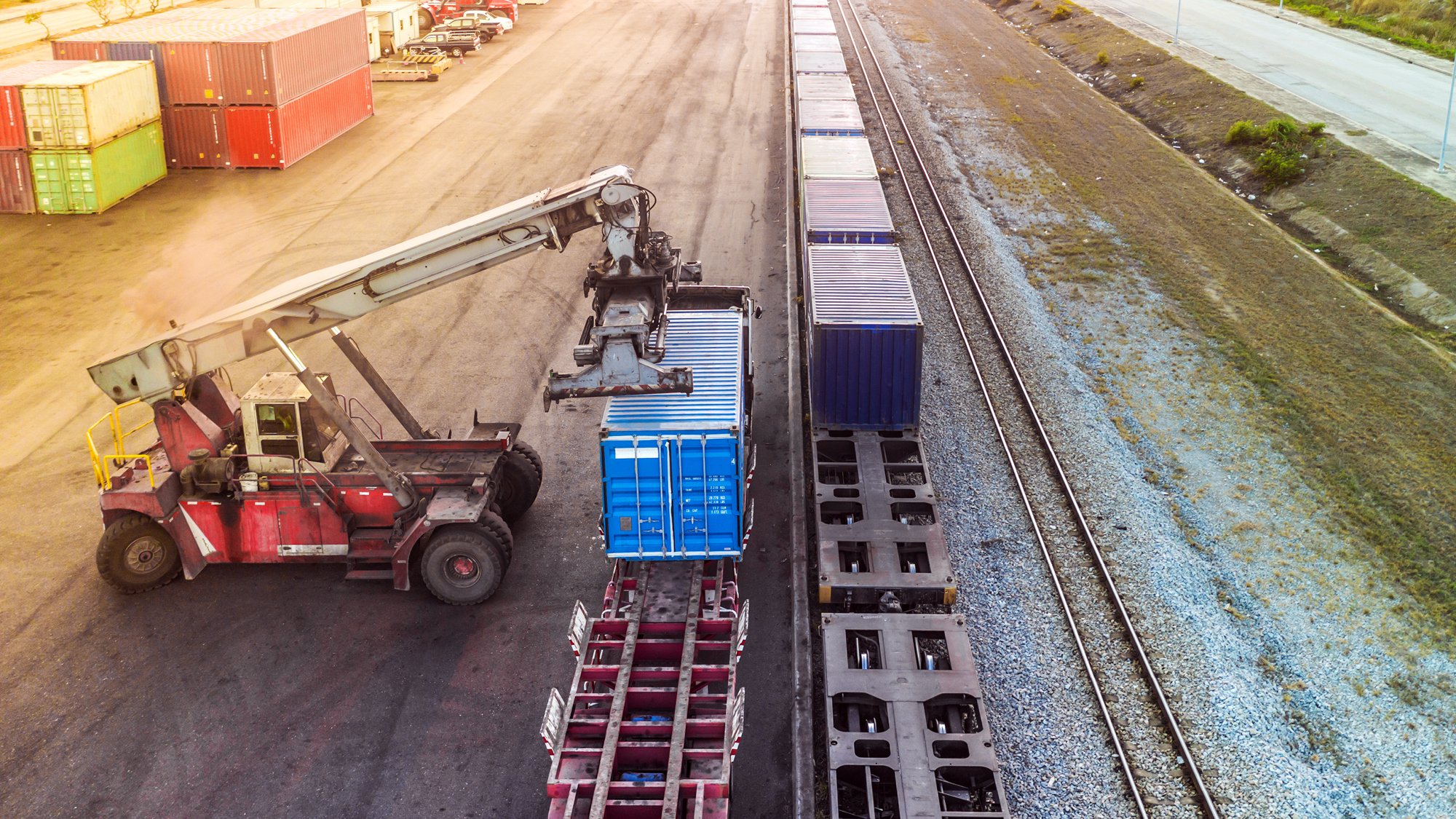 Forklift lifting shipping container onto a train for rail freight