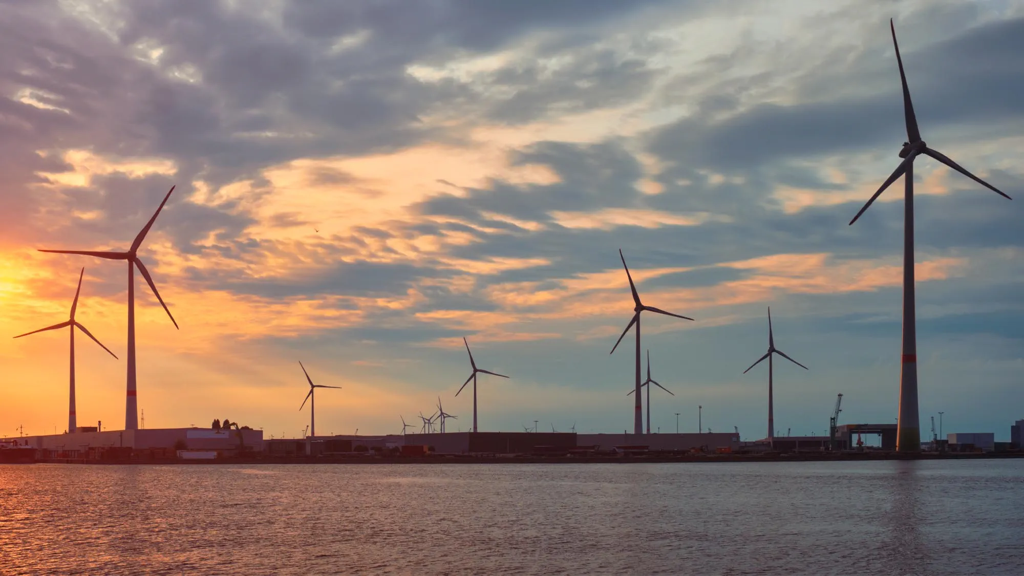 Wind turbines power electricity generators in Antwerp port on sunset. Credit: Shutterstock
