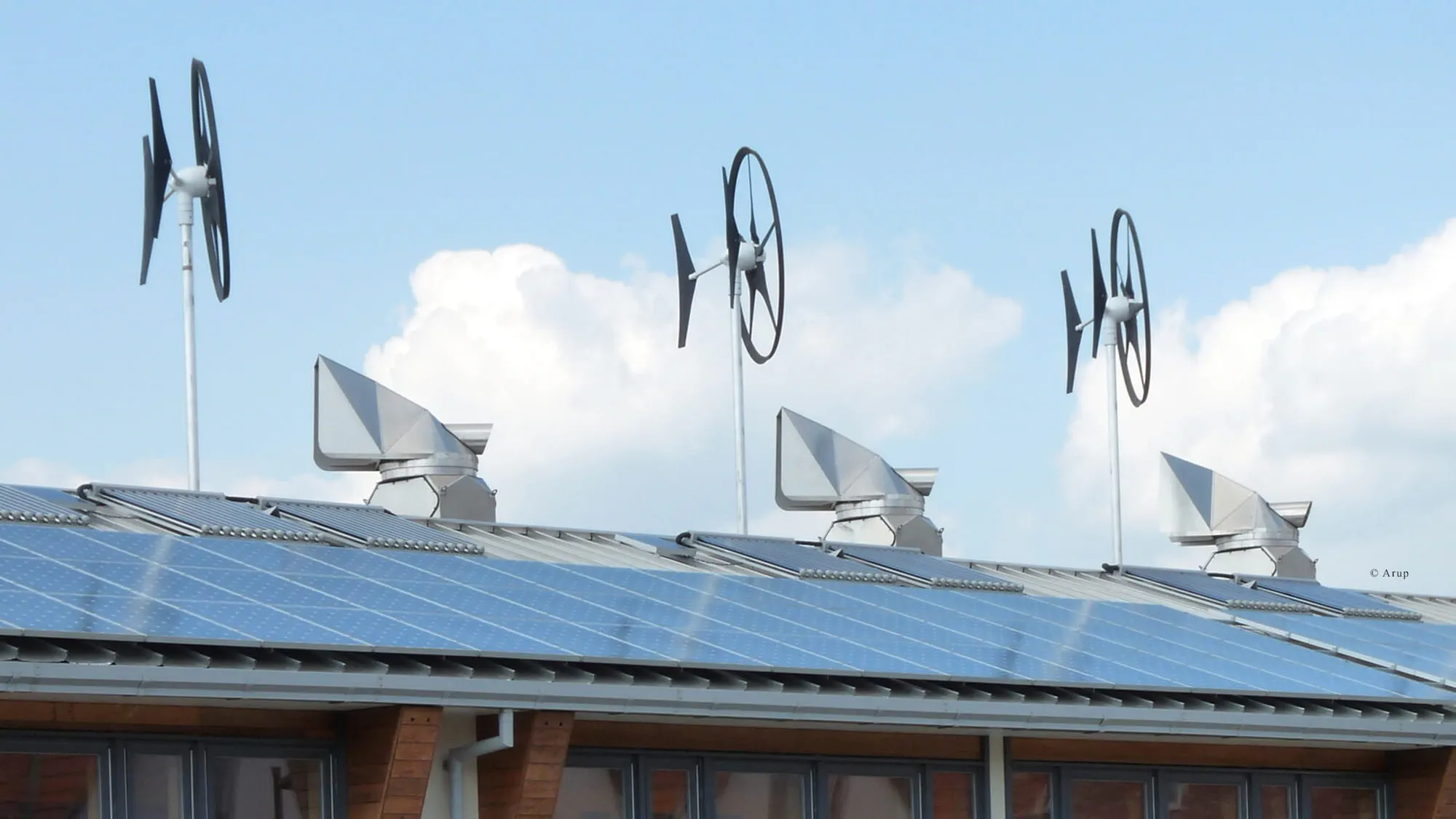 Wind turbines and solar panels on the roof of a house.