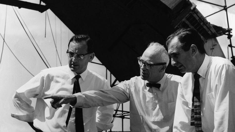 Black and white photograph dated 1966 with three middle aged men outside in day time pointing at something
