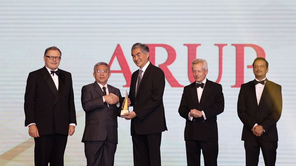 five men in suits on a stage accepting an award