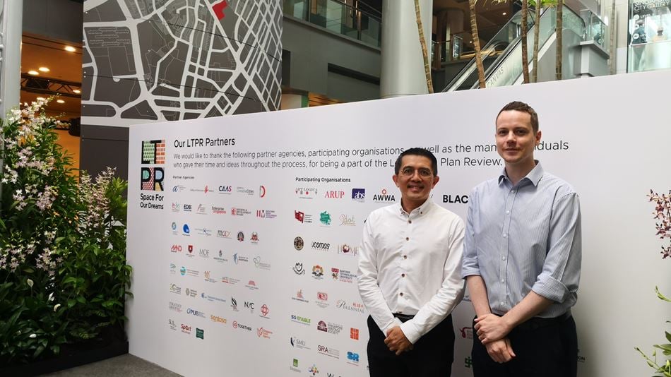 Two men standing in front of a media wall at an event in Singapore
