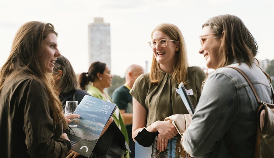 Three women smiling and talking at an event in day time