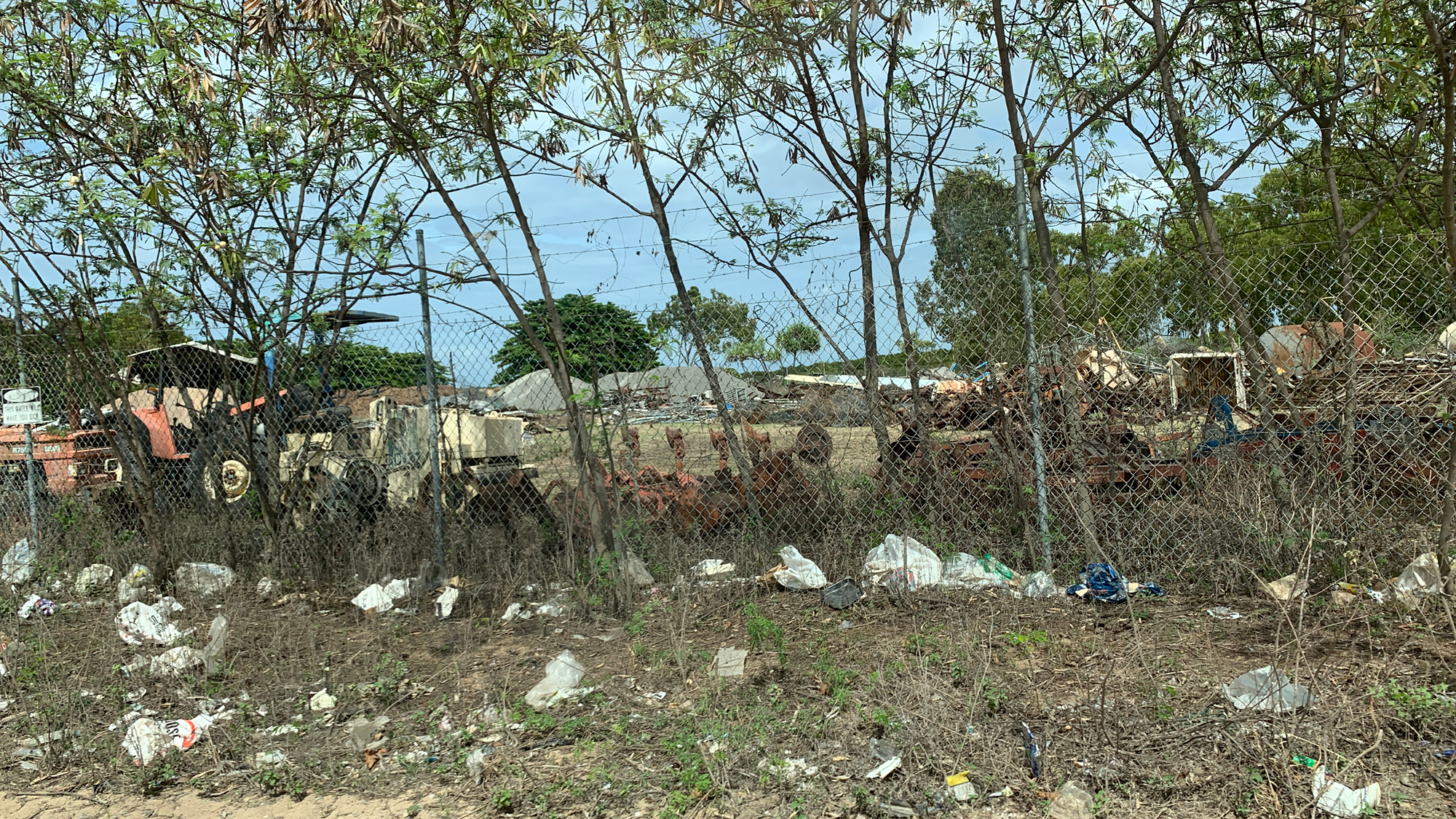Rubbish, plastic bags scattered along fence