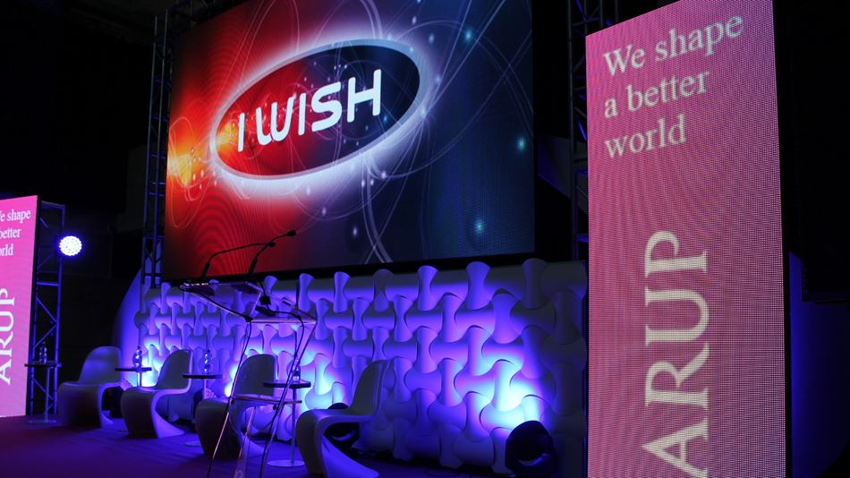 I Wish stage showing Arup logo and 'We shape a better world' on two LED monitors on either side.