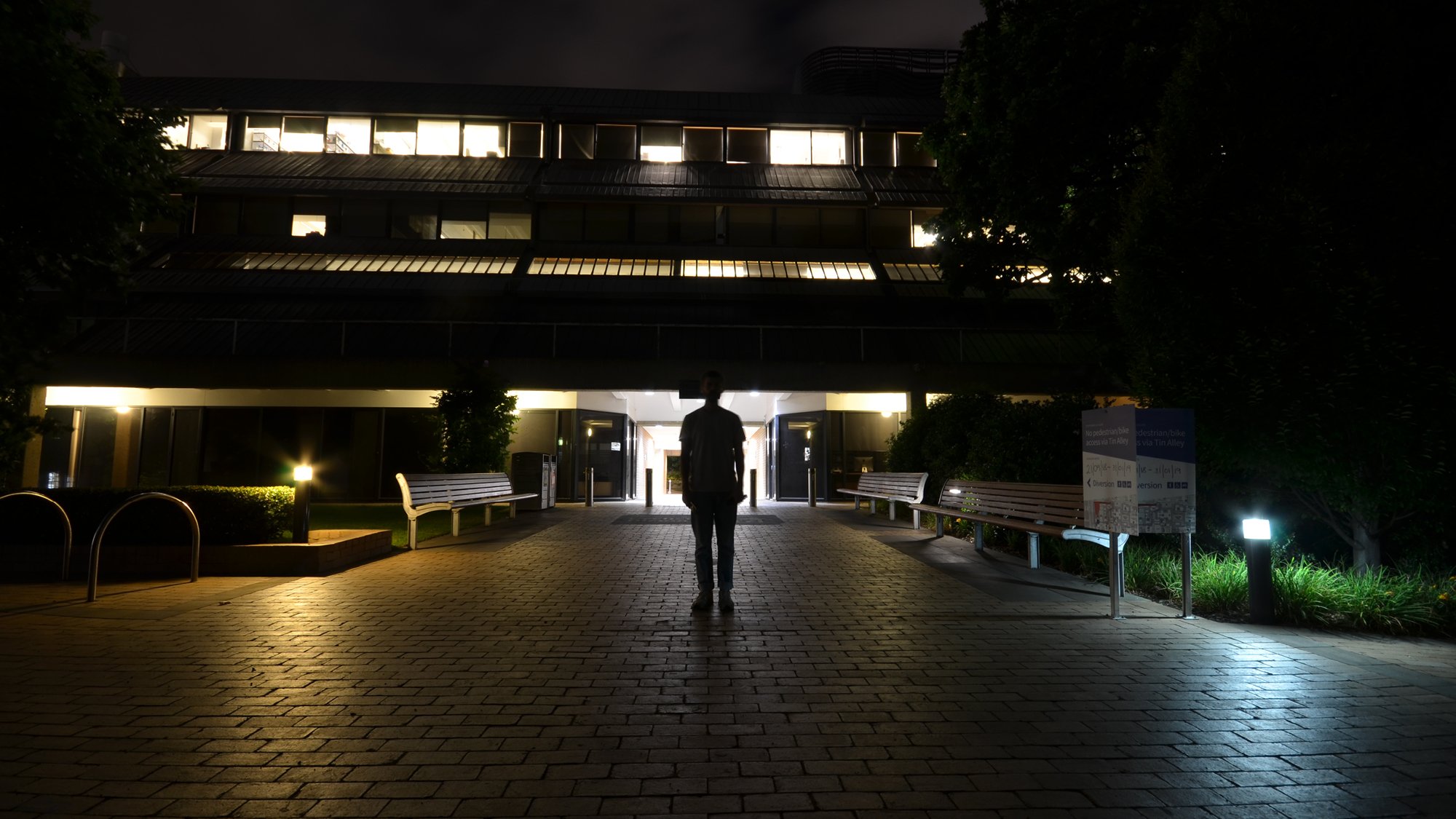 Man standing in front of poorly lit building at night