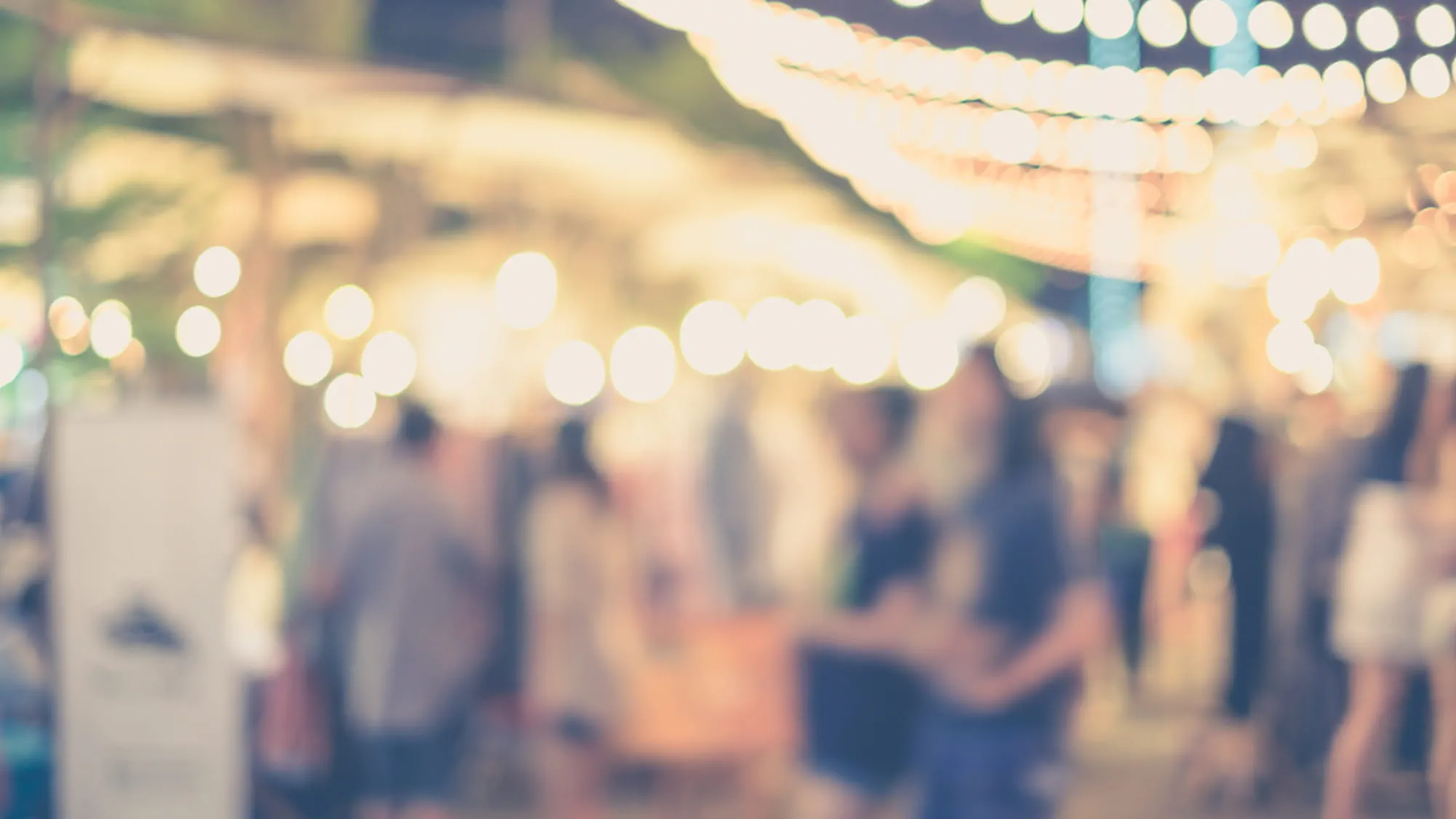 Blurred photgraph of people enjoying a night market under lights