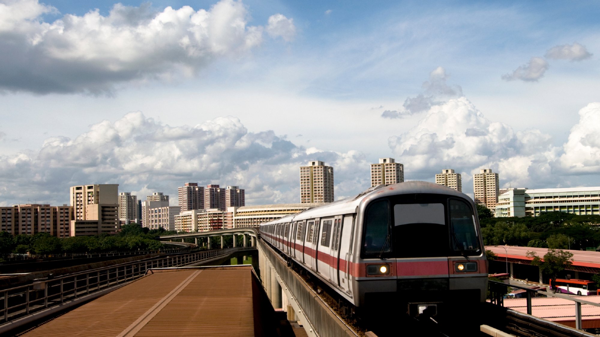 Daytime photograph of Singapore city with train on platform in foreground