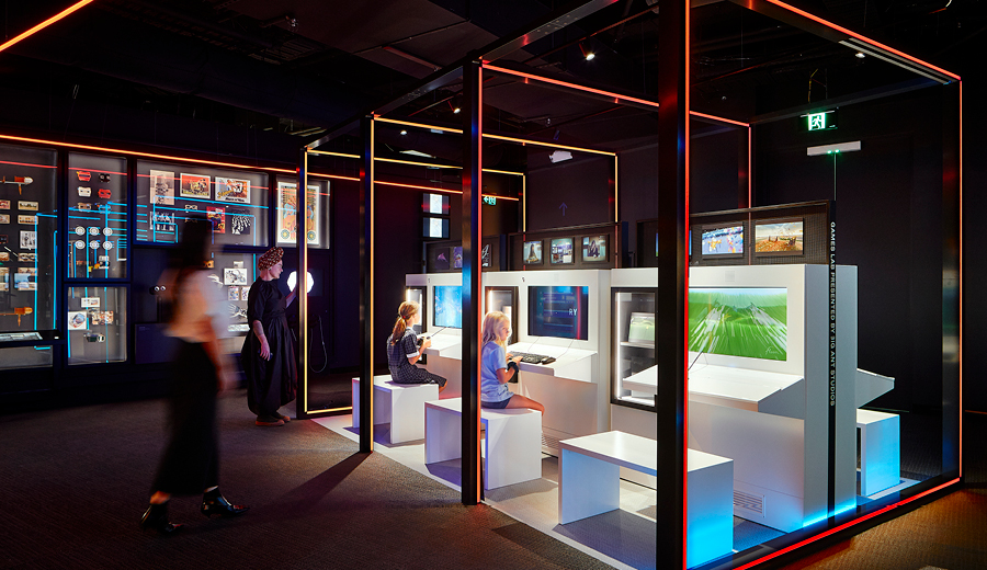 Children sitting in front of screens reading and playing inside an exhibition