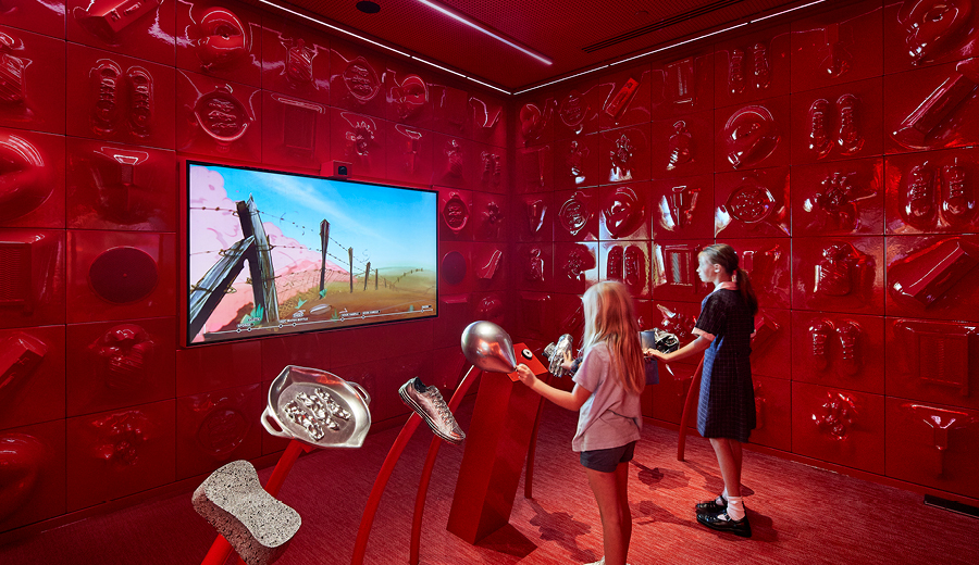 Children playing a game looking at a large screen in a red room