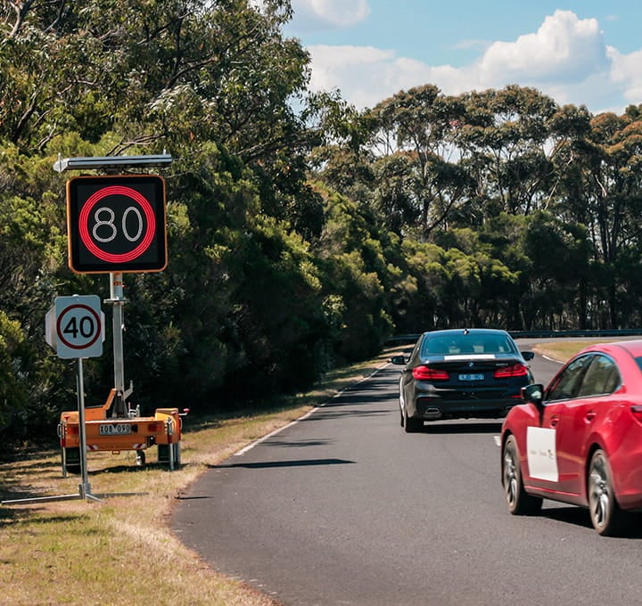 Trial autonomous vehicles on a road passing a static 40km/h sign and an eletronic 80km/h sign