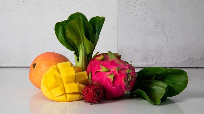 A group of tropical fruits and vegetables on a plain white table