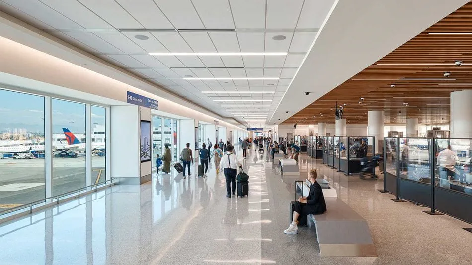 View of airport terminal hallway, with large windows to tarmac on left and TSA security on right