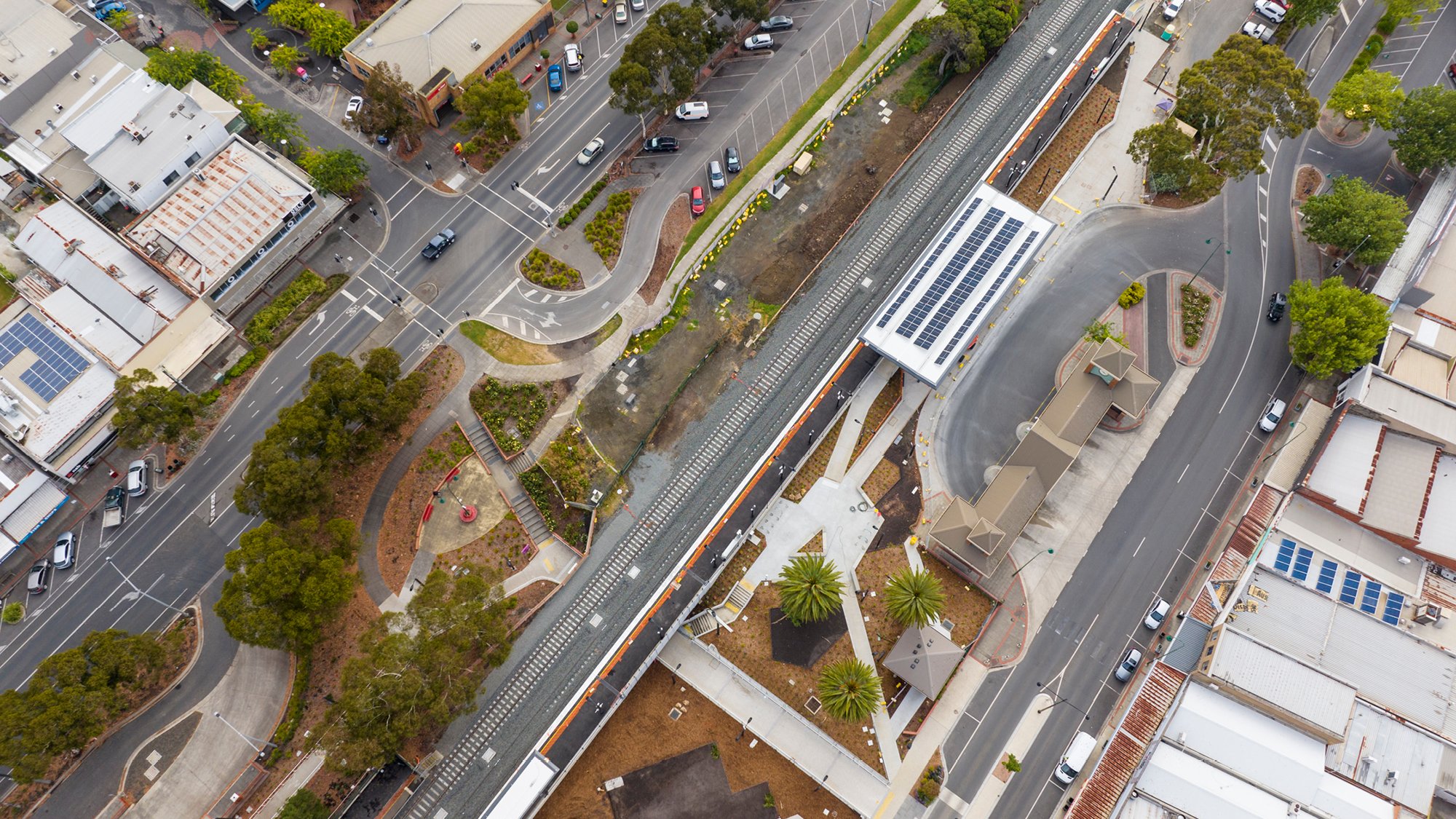 aerial view over a rail line with station, parklands nad roads