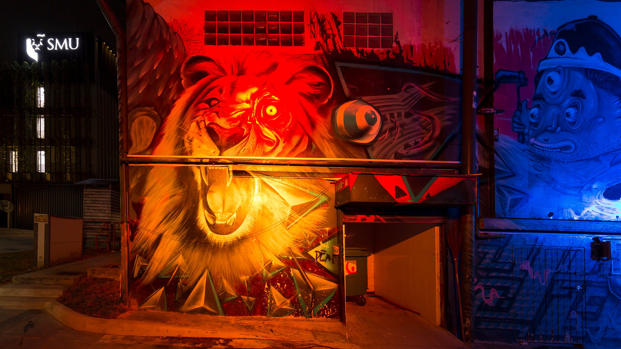 Night time photo of a graffiti lion lit up by coloured spot lights