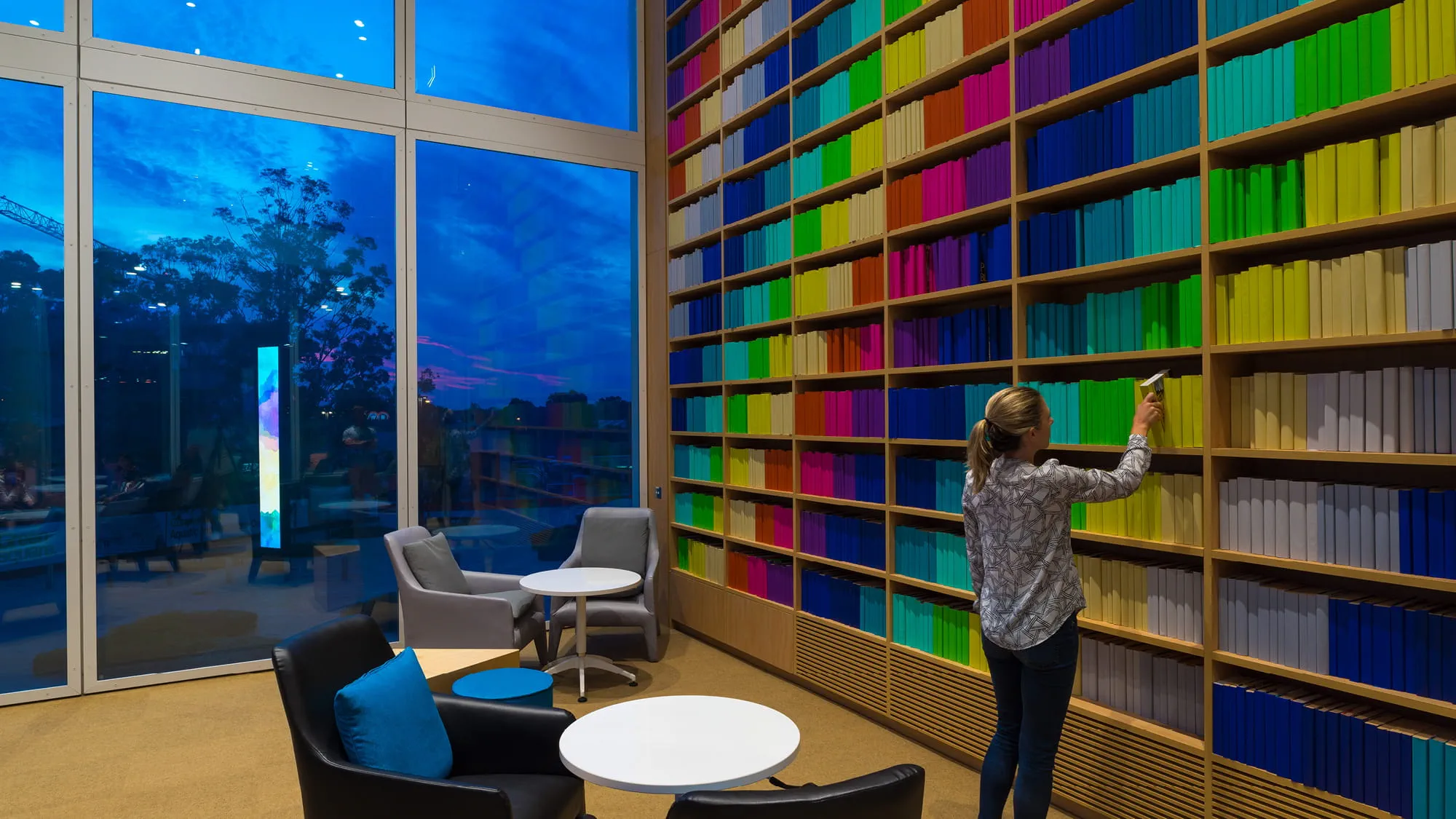 A woman browses colourful shelves inside Green Square Library