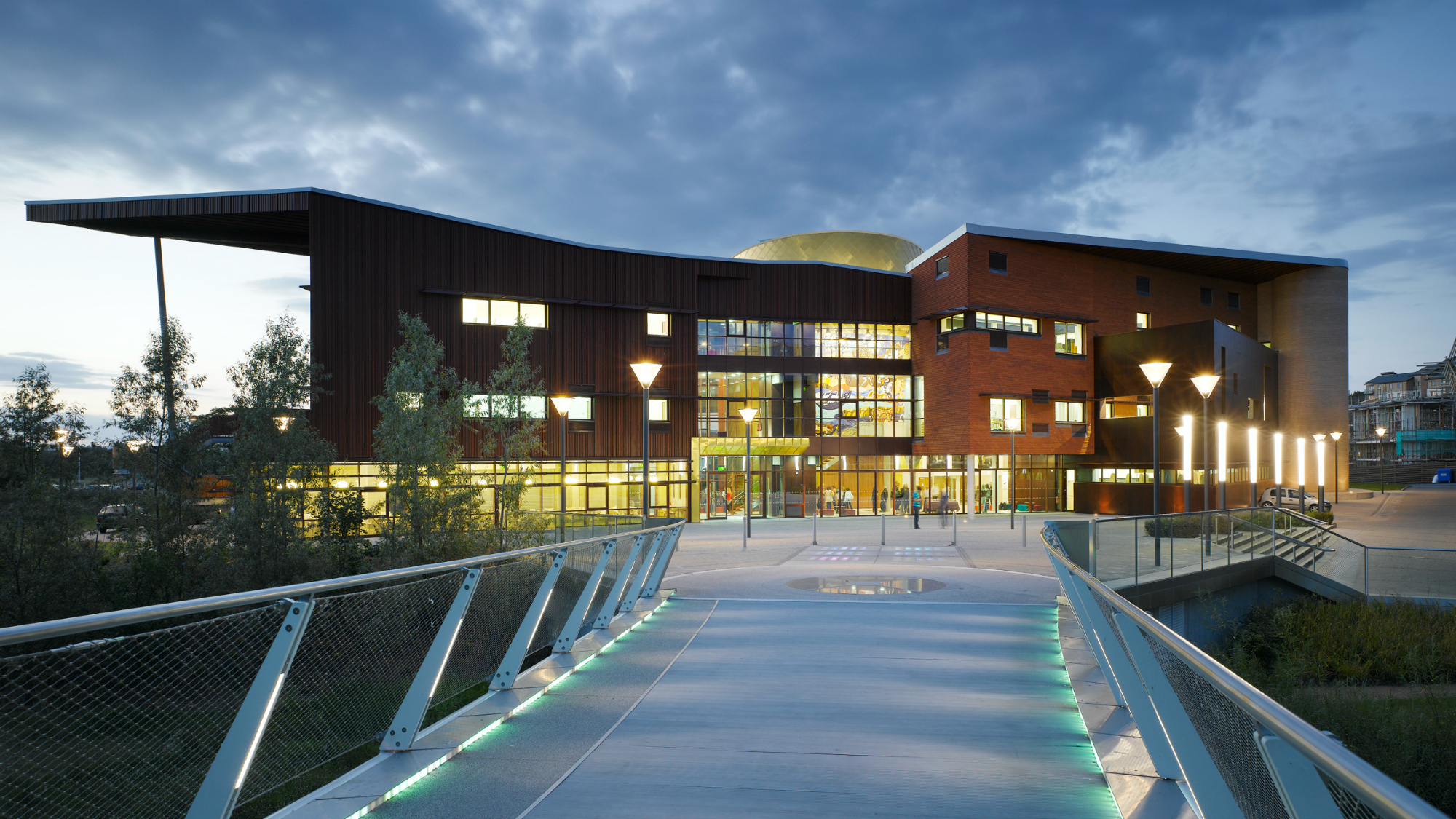 Exterior view at night-time of the Irish World Academy of Music and Dance showing a bridge in the foreground.