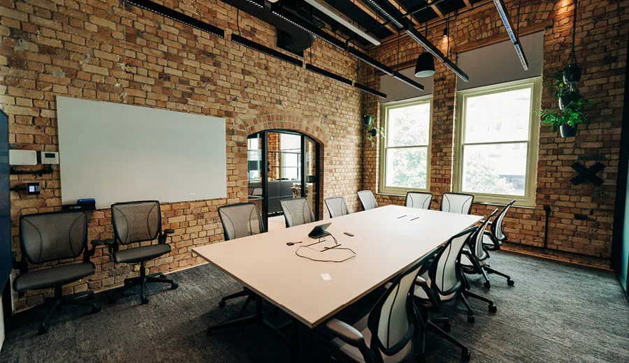 Meeting room with large table and desks, plants, natural daylight