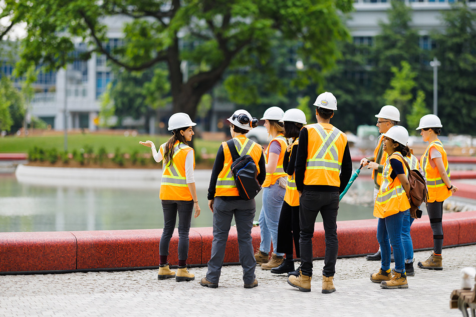 Several people wearing site safety gear visit an urban park