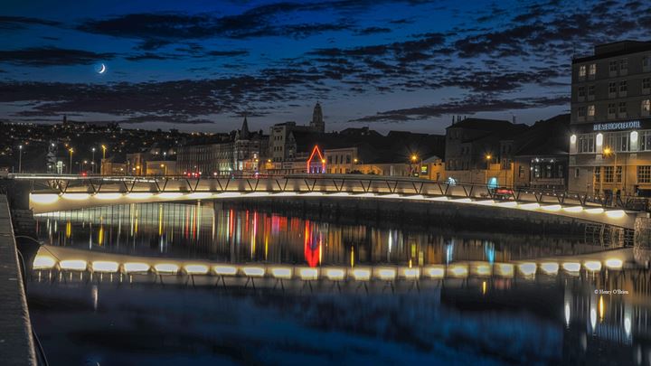 Night-time view of Mary Elmes Bridge showing lighting reflected in the River Lee.