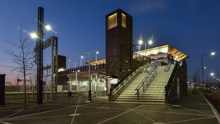 Meridian Water station at night showing illuminated roof and tower. 