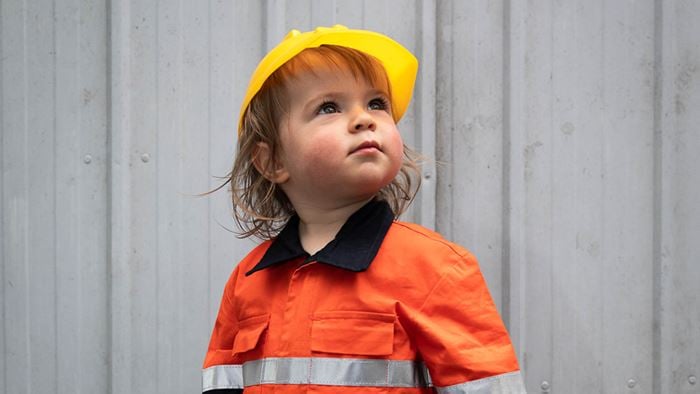 A young boy wearing high visibility clothing and a hard hat