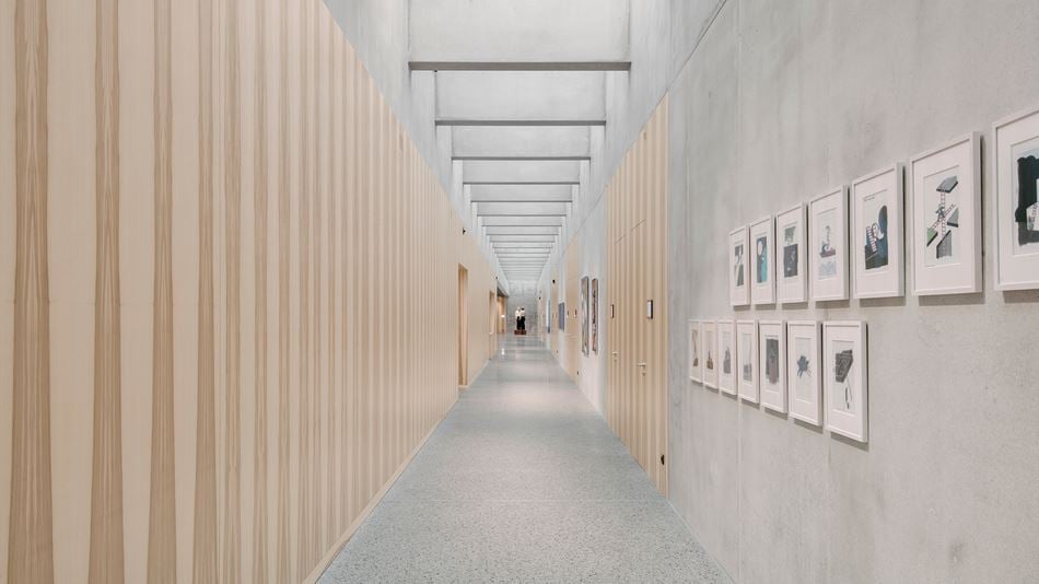 The windowless corridor leading to the conference area is clad in light wood on one side, while the other side and ceiling are made of beton brut.
