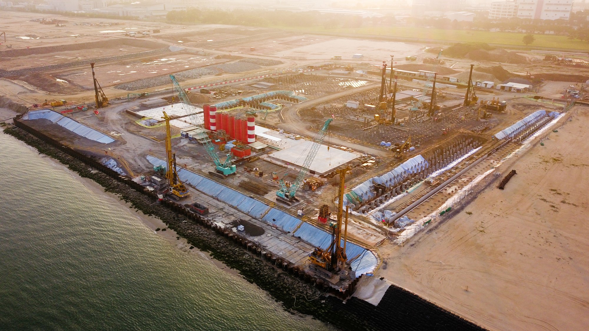 A very large construction site on the coast. The site is for the Offshore Marine Centre 2 Singapore.