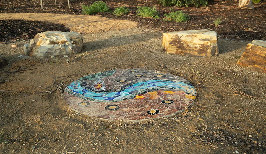 Local Indigenous stories, knowledge and art are located throughout the precinct at Ovingham Rail Station. This is a circular tiled paving piece of art.