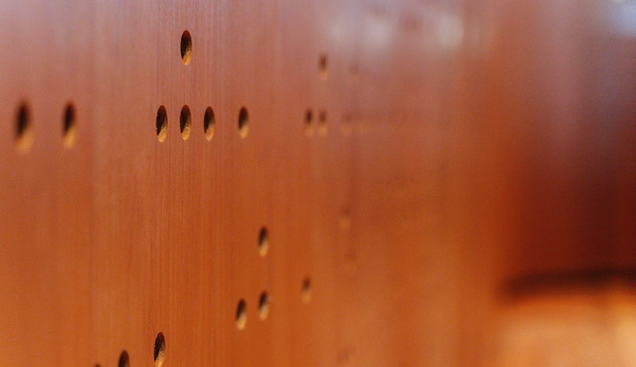 Timber panel wall with hidden messages in braille and Morse Code containing famous quotes from composers.
