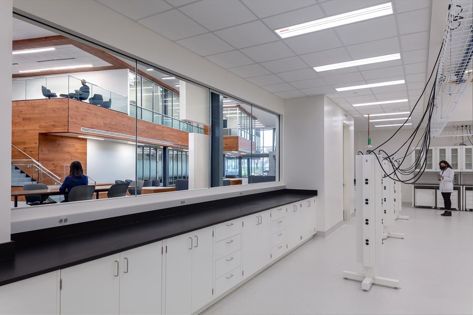 Interior view of PNNL lab with white floors, a long work bench, lab equipment, and a glass window looking out into the lobby.