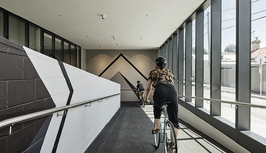 A woman rides a bicycle down a ramp inside a building