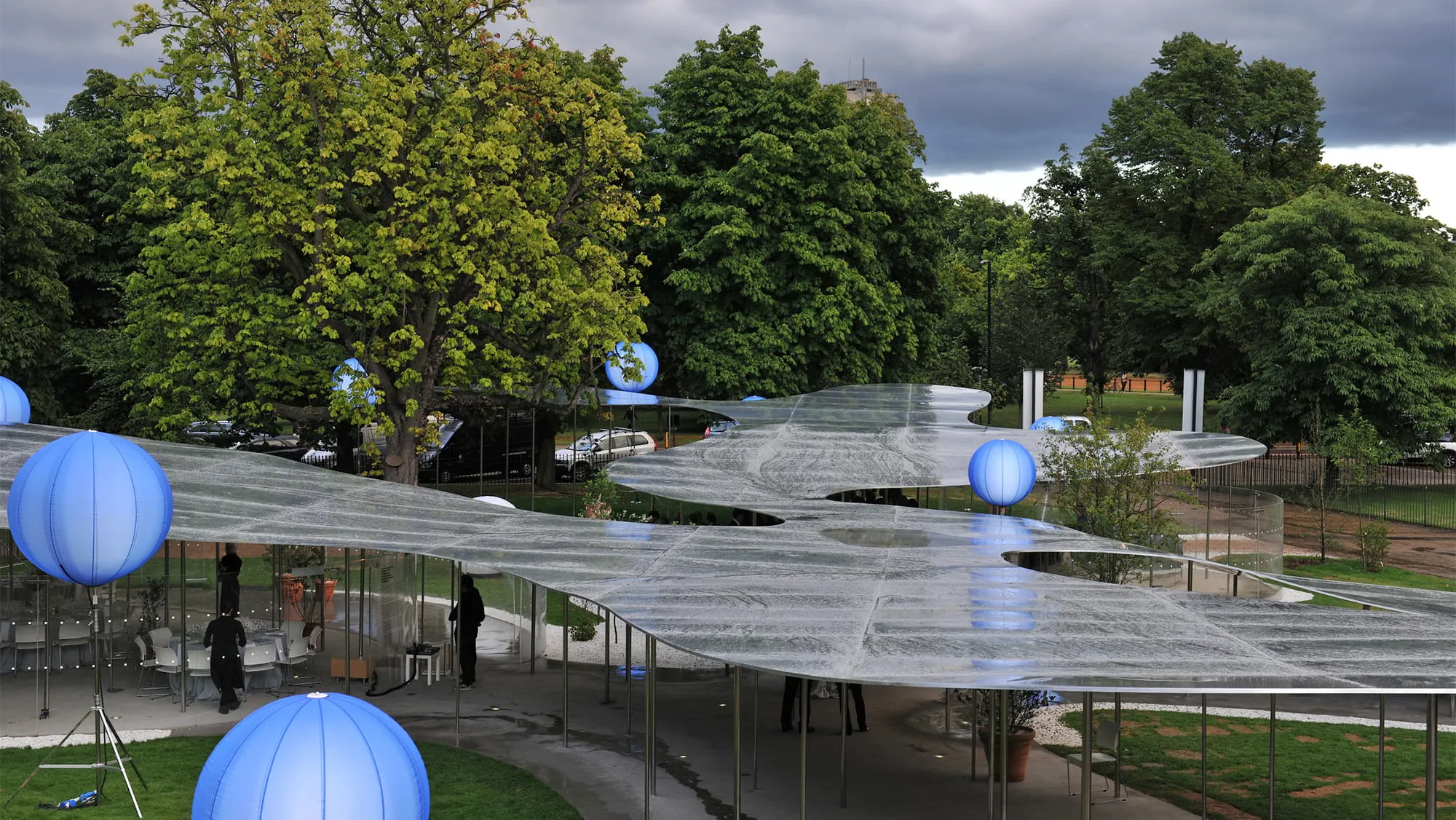 The 2009 Serpentine Pavilion resembles a reflective cloud or a floating pool of water, sitting atop a series of delicate columns. The aluminium roof structure varies in height, wrapping itself around trees in the park. Photo: Daniel Imade