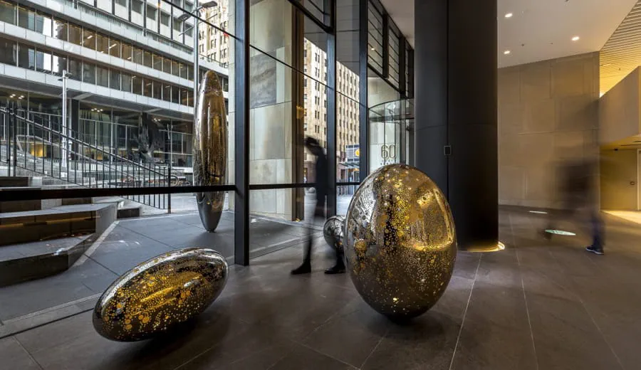 Inside the foyer of Sixty Martin Street Sydney with gold, reflective, scultural forms as a centrepiece of art