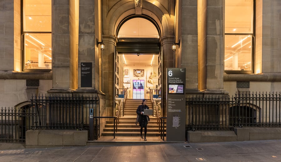 Woman walking down the stairs at the entrance of the State Library Victoria, Melbourne at dusk