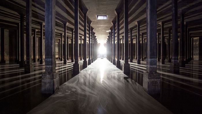 Inside a dark, large cavernous space with shiny floors and pillars. The space is empty, but very dramatic. 