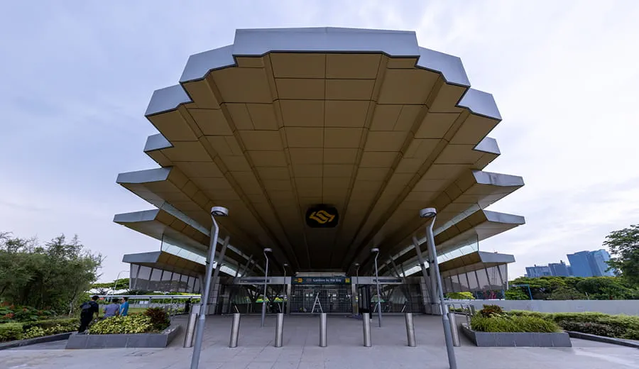 View looking up at roof line over train station entrance in Singapore. The free standing roof is large, decorative and cantilevers over the entrance steps. 