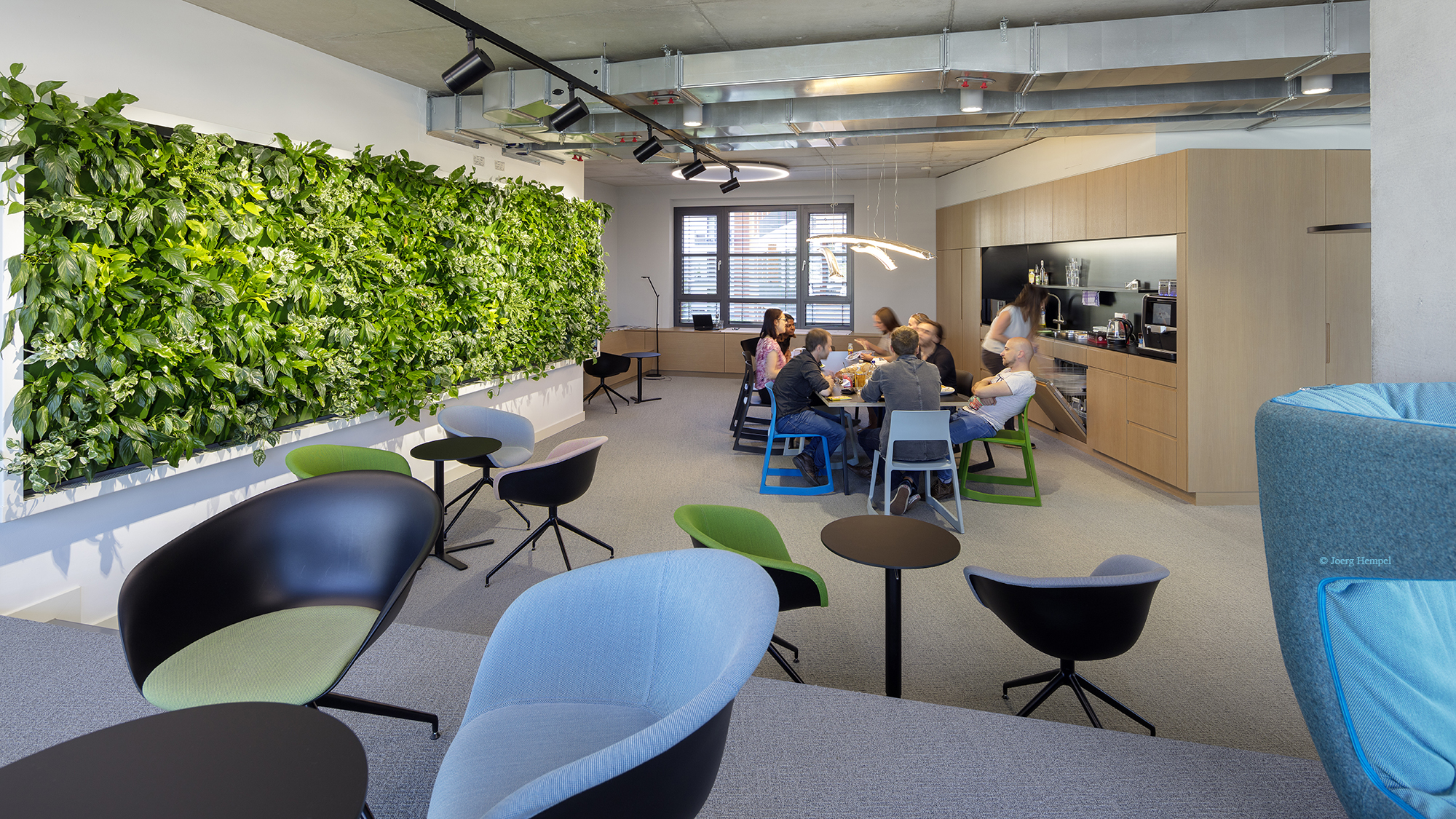 The employees' lounge of the Frankfurt office with its green café, communal lunch table and seating arrangements invites people to meet in a relaxed atmosphere. 