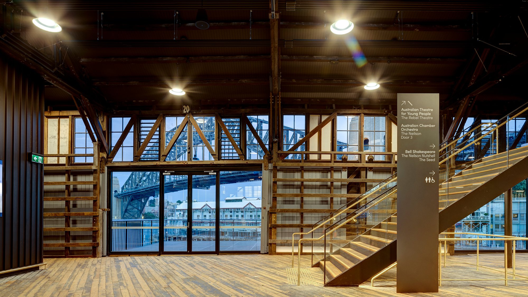 Inside a restored timber building at Walsh Bay Arts Precinct, with Sydney Harbour Bridge in the background viewed through the window