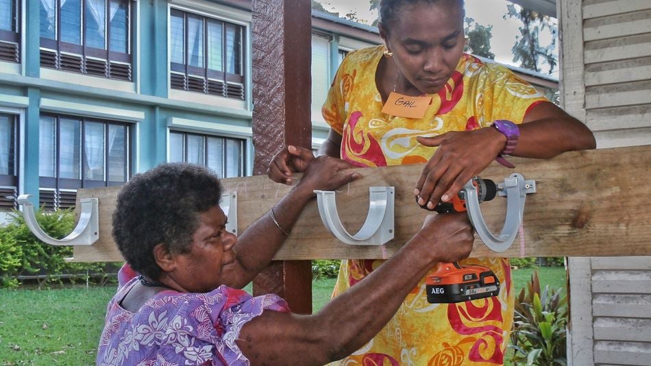Two Vanuatuan women working together using a drill