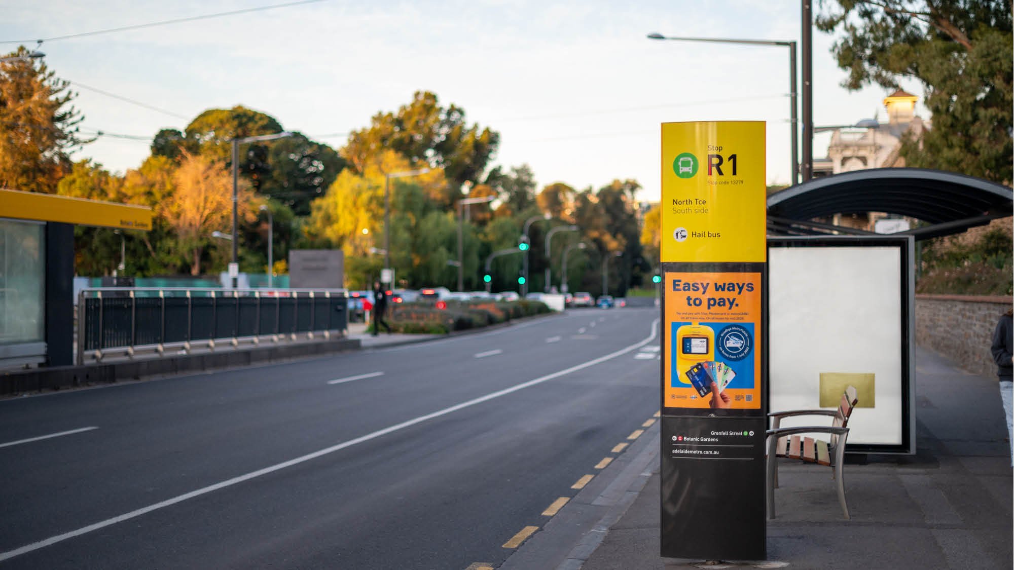 A street in Adelaide city with bus stop and large signage, at dusk