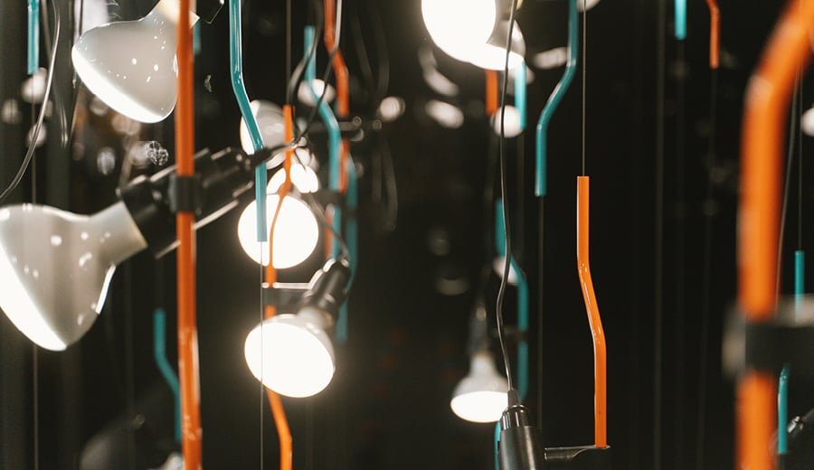 An installation of hanging light bulbs with coloured electrical power leads - orange and blue