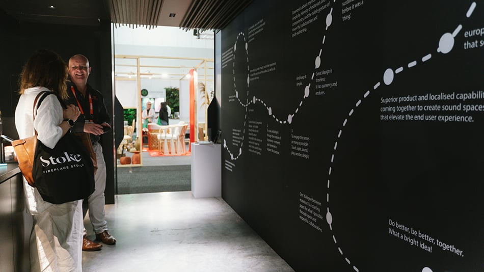 People looking at a black wall with white writing and lines,  showing the journey of the design of a lighting exhibition