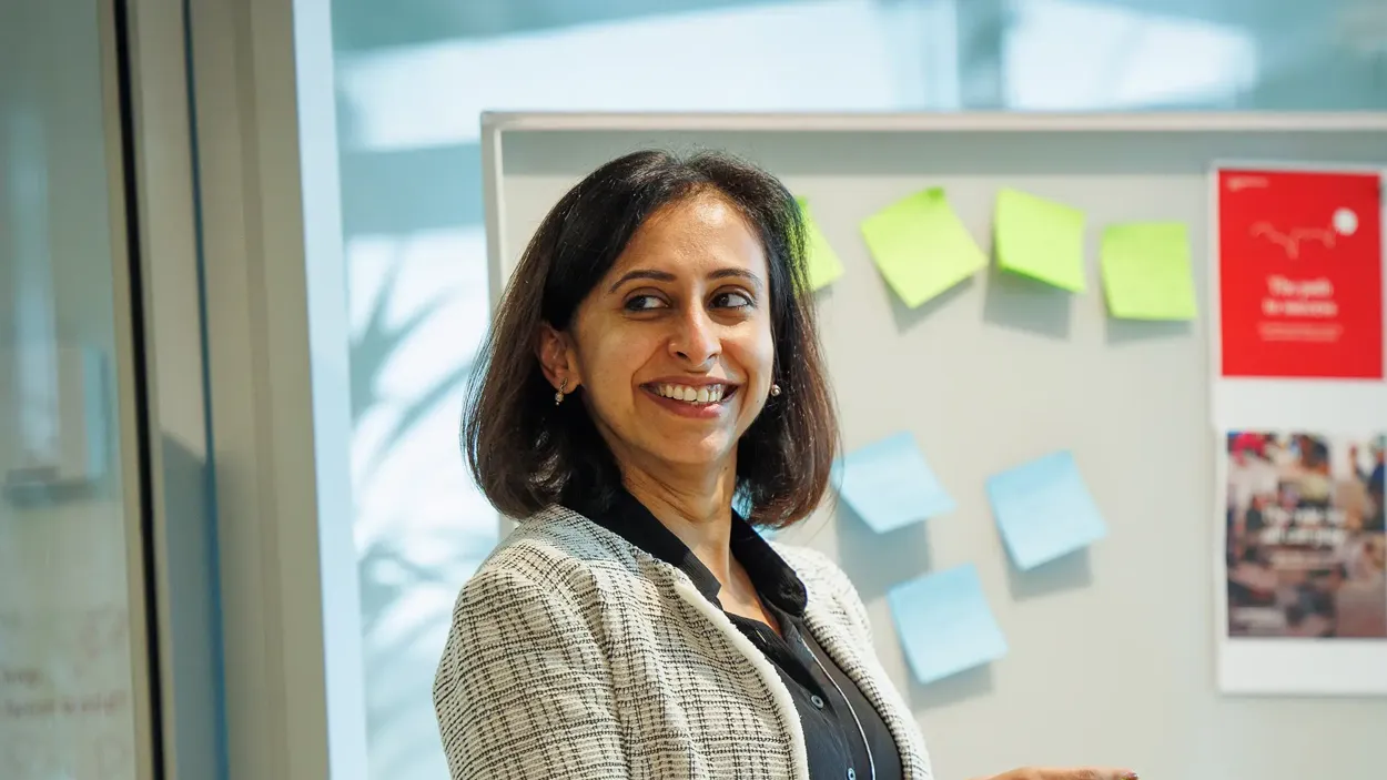 A woman smiling in front of a white board.