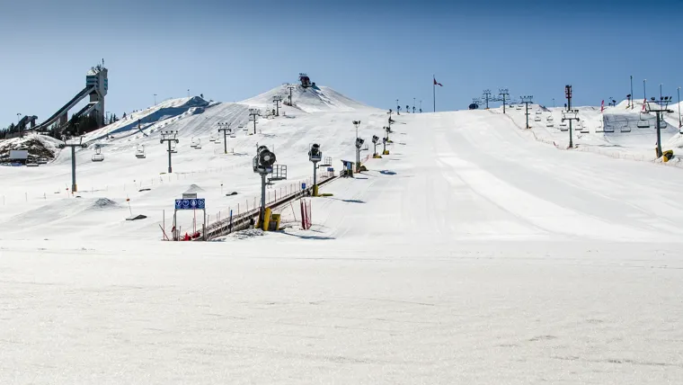 A ski lift going up a snowy hill.