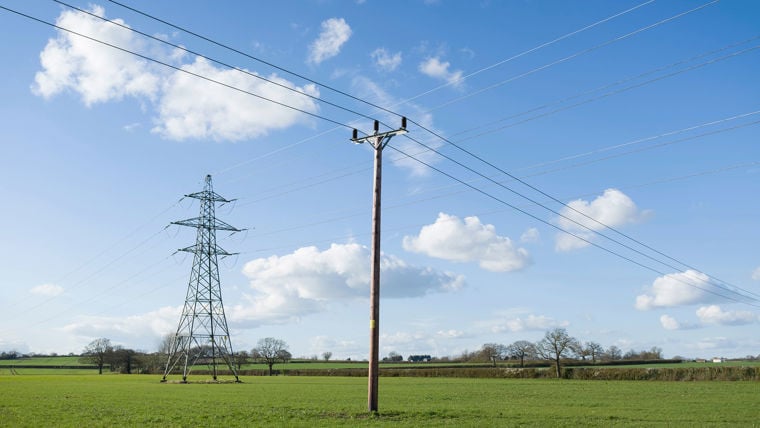 Power lines on poles in a field with Moonlight tower in the background.