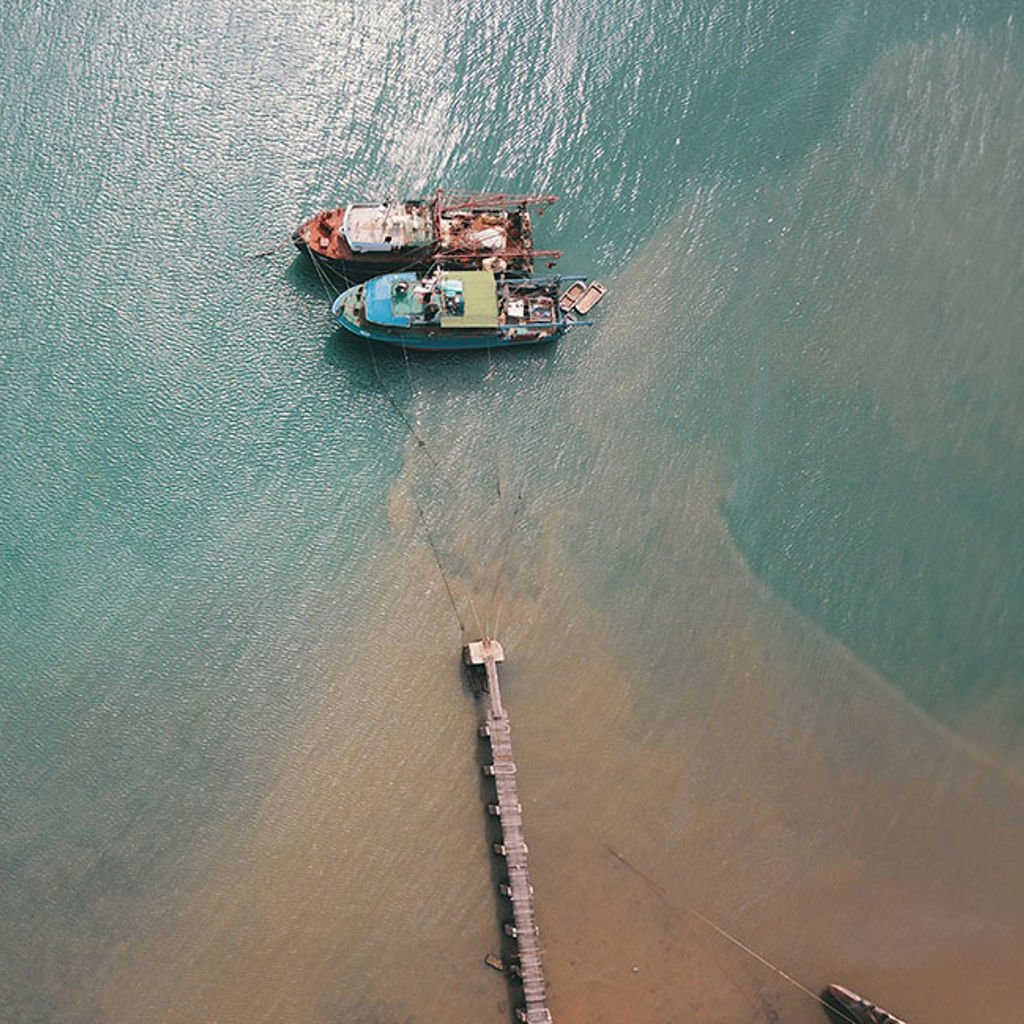 Aerial view looking down on the sea with ships off a pier